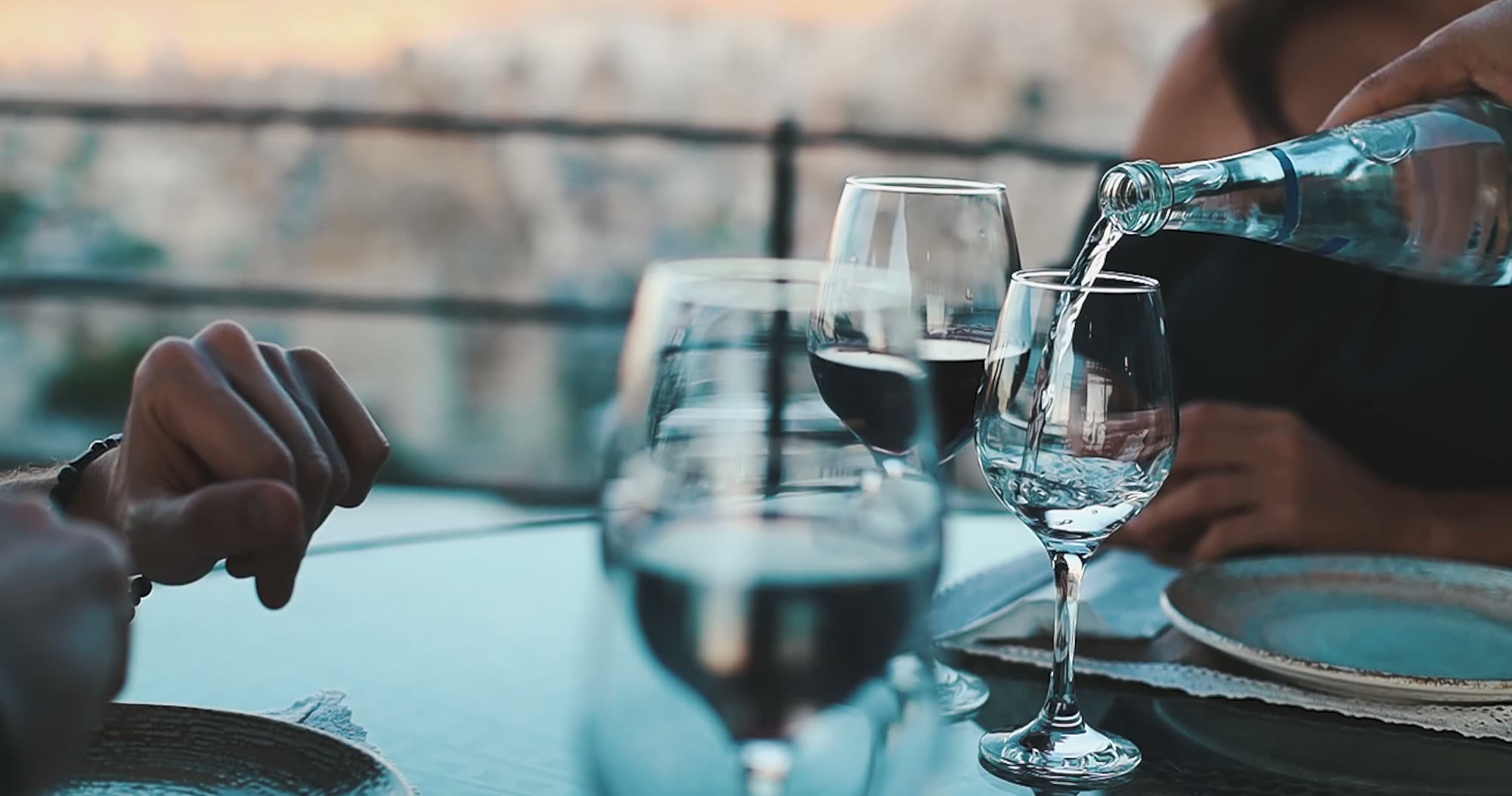 A waiter pouring wine at a table set by the sea